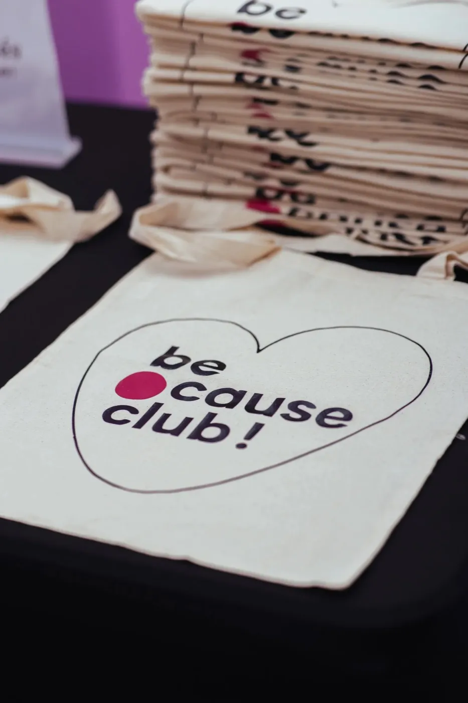 Une pile de tote bags du club sur un stand, cœur et logo imprimés